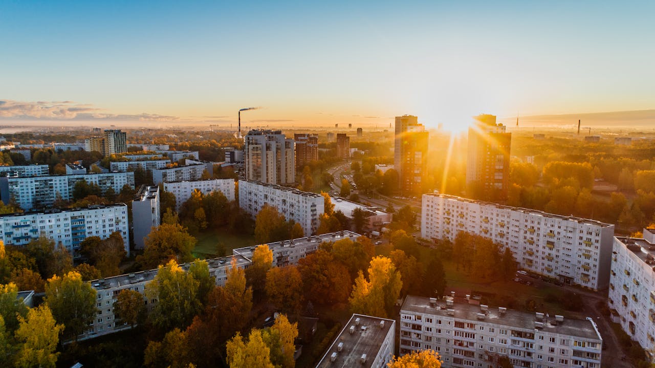 about-01 Aerial view of a cityscape at sunrise with autumn foliage and modern buildings.